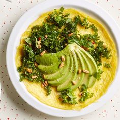 a white bowl filled with guacamole and sliced avocado on top