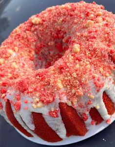 a red velvet bunt cake with white frosting and sprinkles on top