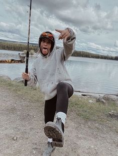 a woman holding a fishing pole and pointing at the camera