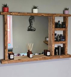 a wooden mirror with shelves and candles on the shelf in front of it, along with an air plant