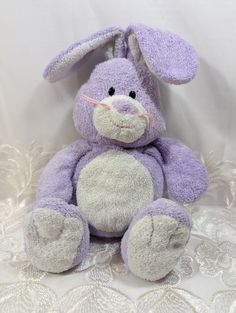 a purple stuffed animal sitting on top of a white lace covered tablecloth with an eye patch