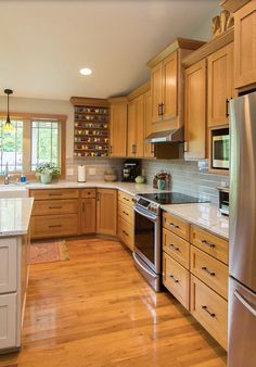 a kitchen with wooden cabinets and stainless steel appliances in the center, along with hardwood flooring