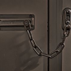 a black metal door with a chain hanging from it's side and a lock on the front