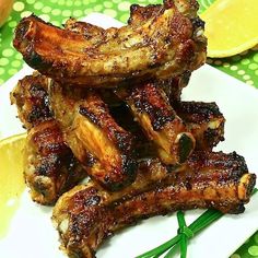 grilled chicken wings on a white plate with lemon wedges