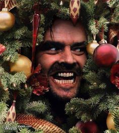 an image of a man peeking out from behind a christmas tree