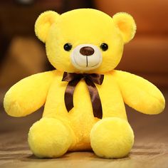 a yellow teddy bear with a brown bow on it's neck sitting on the floor