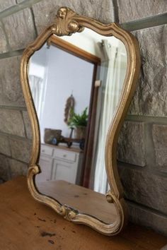 a mirror sitting on top of a wooden table next to a brick wall with a potted plant in it