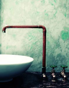 a white sink sitting under a faucet next to a green wall