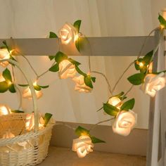 white roses with green leaves are lit up on the wall next to a wicker basket