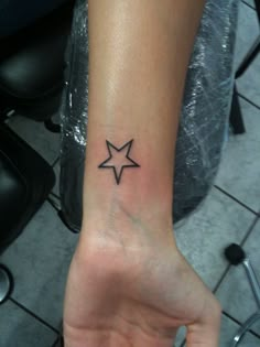 a small star tattoo on the wrist is shown in black ink, and it appears to be an arrow