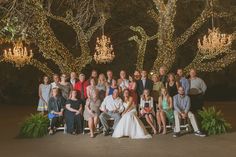 a large group of people are posing for a photo in front of some chandeliers