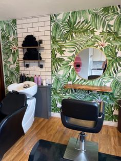 a hair salon with palm leaves on the wall and wooden flooring in front of it