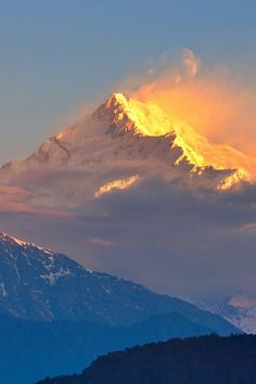 the top of a mountain covered in snow under a cloudy sky at sunset or sunrise