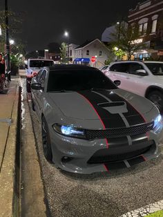 several cars are parked on the side of the road at night in front of some buildings