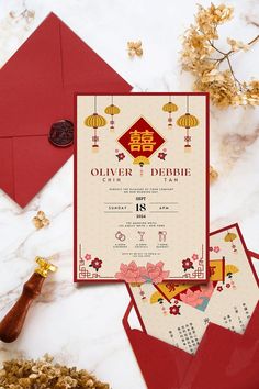 the wedding card is on top of some red envelopes and gold foiled decorations