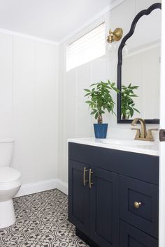 a white toilet sitting next to a blue cabinet in a bathroom under a large mirror