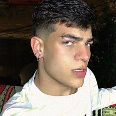 a close up of a person wearing a white shirt and black hair with an earring