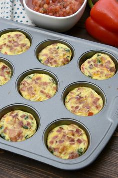 muffin tins filled with breakfast food sitting on top of a wooden table