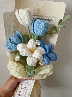 a crocheted flower bouquet is held by someone's hand with a card