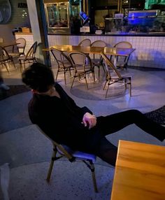 a woman sitting on a chair in front of a table with chairs around her and tables to the side