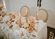 flowers and candles on a table with white linens