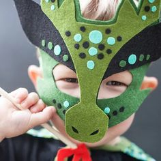 a young boy wearing a green and black mask