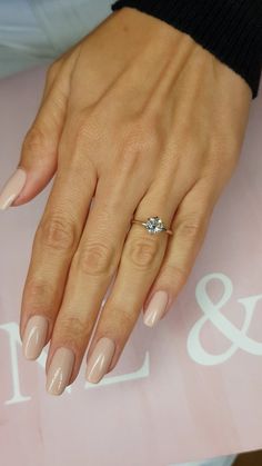 a woman's manicured nails with a ring on top of her finger and an engagement ring in the middle