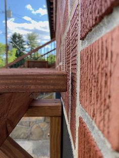 a wooden bench sitting next to a red brick wall with stairs in the back ground