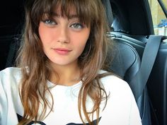 a young woman sitting in the back seat of a car looking at the camera with an intense look on her face