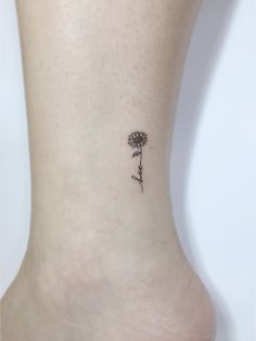 a small flower tattoo on the ankle that is very feminine and delicate, it looks like a dandelion