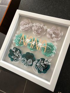 there is a shadow box with flowers in it and the word anan on it