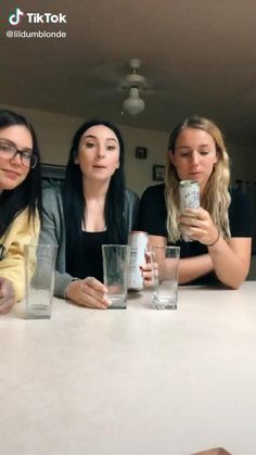 three women sitting at a table drinking from cups