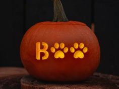 a carved pumpkin with paw prints on it and the word boo spelled in yellow light