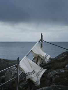 two cloths are hanging on a clothesline near the ocean under a cloudy sky