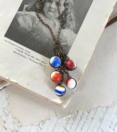 a book with a necklace on top of it next to an old sheet of paper