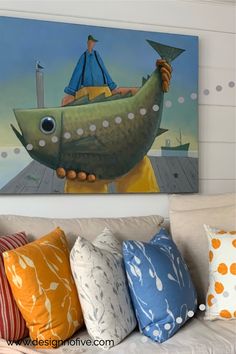 a painting on the wall above a couch in a living room with colorful pillows and throw pillows