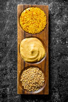 three different types of food on a wooden plate with spoons next to each other