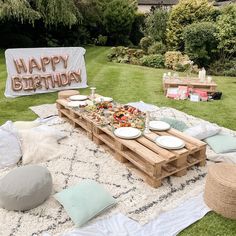 an outdoor birthday party with food and decorations on the grass in front of a sign that says happy birthday