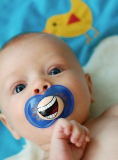 a smiling baby with a pacifier in his mouth