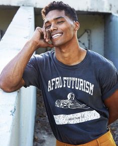 a young man leaning against a rail talking on a cell phone with his hand to his ear