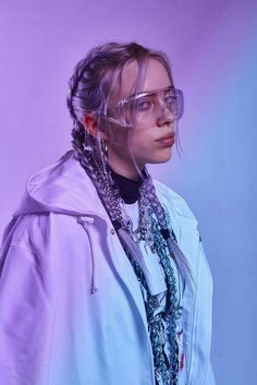 a woman wearing glasses and a scarf around her neck is posing for a photo in front of a purple background