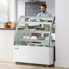 a man standing in front of a display case filled with cakes