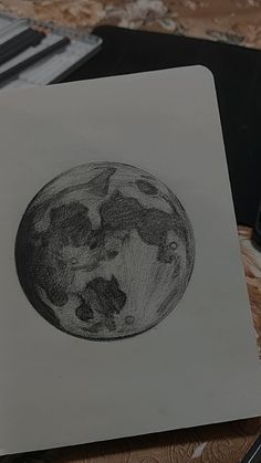 a pencil drawing of the earth on a piece of paper next to a cell phone