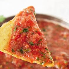 a tortilla chip being dipped with salsa