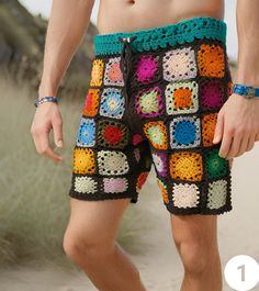 a man wearing shorts with crocheted squares on the bottom and sides, standing in sand