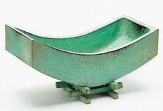 a green bowl sitting on top of a metal stand