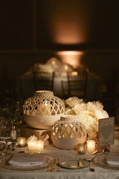 the table is set with candles, plates and vases for an elegant wedding reception