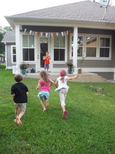 three children running in front of a house