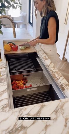 a woman standing in front of an open grill with fruit and vegetables on the counter