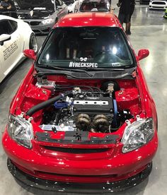 a red car with its hood open in a showroom